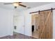 This bedroom features wood-look floors, a ceiling fan, and a unique barn door to the ensuite bathroom at 949 Andalusia Loop, Davenport, FL 33837