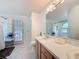 Bathroom with dual sinks, white countertop, wood cabinets, and access to shower and outside at 129 Pine Lake View Dr, Davenport, FL 33837