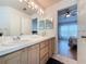 Bathroom with dual sinks, wood cabinets, large mirror, and an open doorway to the bedroom at 129 Pine Lake View Dr, Davenport, FL 33837