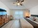 Well-lit bedroom featuring a ceiling fan, wood dresser with TV, and a cozy chair by the window at 129 Pine Lake View Dr, Davenport, FL 33837