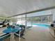 A covered patio area with a table, chairs, and lounge chairs, perfect for outdoor dining and relaxation by the pool at 129 Pine Lake View Dr, Davenport, FL 33837