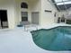 This in-ground pool sits next to a beige home with a screened lanai and sliding glass doors at 132 Santana Pl, Davenport, FL 33897
