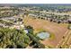 Aerial view of tennis courts, green spaces, and a residential area with well-maintained homes and roads at 16014 Hawk Hill St, Clermont, FL 34714