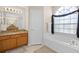 Bright bathroom featuring a soaking tub, granite vanity, and decorative window with modern tile flooring at 16014 Hawk Hill St, Clermont, FL 34714