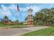 Community entrance featuring a brick sign, manicured landscaping, and a prominent tower structure at 16014 Hawk Hill St, Clermont, FL 34714