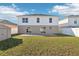 View of the backyard featuring a grassy lawn, patio area, shed, and the home's exterior with sliding glass doors at 16035 Wilkinson Dr, Clermont, FL 34714