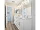 Bathroom with double sinks, white cabinets, and a glass enclosed shower stall at 16035 Wilkinson Dr, Clermont, FL 34714