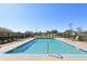 A community pool with lounge chairs, a metal safety fence, and lush green landscaping around the perimeter at 16035 Wilkinson Dr, Clermont, FL 34714