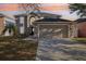 Two story home boasts an arched entry, attached two car garage, and well-maintained lawn against a vivid sunset backdrop at 16035 Wilkinson Dr, Clermont, FL 34714