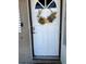 A white front door is adorned with a fall-themed wreath, adding a warm, seasonal touch at 1756 Elbert Acres Ne Ct, Winter Haven, FL 33881
