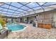Screened pool area with hot tub, patio furniture, and lush landscaping at 2086 Blackfoot Trl, St Cloud, FL 34771