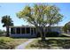 Charming single-story home with large tree in the front yard and a screened-in porch at 2326 S Peninsula Dr, Daytona Beach, FL 32118