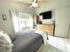 Cozy bedroom with tile flooring, natural light, ceiling fan, and dresser with TV at 2560 Woodgate Blvd # 203, Orlando, FL 32822
