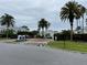 View of the Dockside Condominiums community entrance with a sign and mature palm trees at 2560 Woodgate Blvd # 203, Orlando, FL 32822