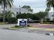 View of the Dockside Condominiums community entrance with a sign and well maintained landscaping at 2560 Woodgate Blvd # 203, Orlando, FL 32822