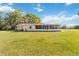 Large, grassy backyard with the home and screened-in lanai on a sunny day, perfect for outdoor enjoyment at 3260 Osceola Rd, St Cloud, FL 34772