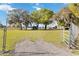 Gated entrance offering a full view of the property with sheds and metal buildings surrounded by lush trees at 3260 Osceola Rd, St Cloud, FL 34772