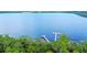 Aerial view showcasing a pier and access to a calm lake surrounded by lush greenery at 3317 Schoolhouse Rd, Harmony, FL 34773