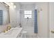 Bright bathroom features white marble tile shower-tub combo and vanity sink with brushed gold fixtures at 3317 Schoolhouse Rd, Harmony, FL 34773