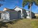Traditional exterior with a clean white garage door, neutral paint, manicured lawn, and attractive landscaping at 334 Sonja Cir, Davenport, FL 33897