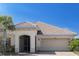 Home exterior featuring a tile roof, arched entryway, attached garage, and well-maintained landscaping at 3818 Carrick Bend Dr, Kissimmee, FL 34746