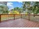 A beautiful wooden deck with black metal and wood railing overlooking the backyard at 415 S 9Th St, Leesburg, FL 34748