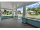 Relaxing front porch view shows blue painted base, light gray flooring and classic columns at 415 S 9Th St, Leesburg, FL 34748