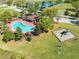 Aerial view of a community pool with red umbrellas, playground and surrounded by lush green grass at 4842 Rockvale Dr, Kissimmee, FL 34758