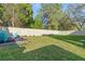 Large, fenced backyard with a grassy lawn and a garden bed featuring colorful Adirondack chairs at 5201 Lake Hinden Cv, St Cloud, FL 34771