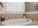A relaxing soaking tub surrounded by stylish tile and featuring a large window for natural light at 5201 Lake Hinden Cv, St Cloud, FL 34771