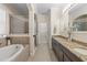 Bright primary bathroom featuring double vanities, granite counters, soaking tub, and glass shower at 5201 Lake Hinden Cv, St Cloud, FL 34771