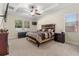 Comfortable primary bedroom with neutral carpet, a ceiling fan, and large windows overlooking the landscaped yard at 5201 Lake Hinden Cv, St Cloud, FL 34771