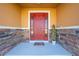 Inviting front porch with stacked stone accents and a bright red front door, creating a welcoming entrance at 550 Michigan Estates Cir, St Cloud, FL 34769