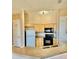 Functional kitchen featuring natural wood cabinets, black appliances, neutral countertops and eat in bar at 619 Terrace Ridge Cir # 619, Davenport, FL 33896