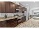 Close-up view of the kitchen featuring granite countertops, stainless steel appliances, and dark wood cabinetry at 6592 Taxiway Cir, Orlando, FL 32822