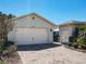 Exterior shot of the property features a two-car garage and well-manicured landscaping at 759 Villa Park Rd, Poinciana, FL 34759