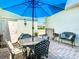 Cozy outdoor patio with a wrought iron table, seating, and a bright blue umbrella for shade at 759 Villa Park Rd, Poinciana, FL 34759