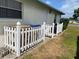 Enclosed trash area with white picket fence adjacent to the house with green lawn at 7794 Indian Ridge S Trl, Kissimmee, FL 34747