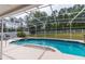 Screened-in pool and spa area with lush landscaping and white picket fence in the background at 7794 Indian Ridge S Trl, Kissimmee, FL 34747