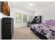Cozy bedroom with purple butterfly-patterned bedding, carpet floors, and a large dresser at 840 Luarca Ln, Oviedo, FL 32765