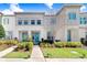 Charming townhome showcases a well-manicured lawn, walkway and vibrant turquoise-colored doors at 8968 Amelia Downs Trl, Kissimmee, FL 34747