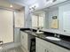 Bright bathroom featuring double sinks with black countertops and a modern shower with glass doors at 910 Spring Park St # 103, Celebration, FL 34747