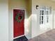 Inviting condo entrance showcasing a vibrant red door adorned with a wreath and a stylish window at 910 Spring Park St # 103, Celebration, FL 34747