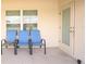 Cozy patio with three blue chairs, and an exterior door leading into the home at 1061 Citrus Landings Blvd, Davenport, FL 33837