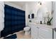 Bathroom featuring a blue shower curtain, white vanity, and a round mirror at 10937 Prairie Hawk Dr, Orlando, FL 32837