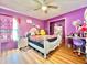 Cozy bedroom with a white bed, wood floors, and a bright purple wall at 12450 Greco Dr, Orlando, FL 32824
