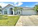 Lovely blue home with a well-kept lawn, palm trees, and a brick-lined driveway at 12450 Greco Dr, Orlando, FL 32824