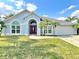 Charming single-story home with a well-manicured lawn, palm trees, and an arched entryway at 12450 Greco Dr, Orlando, FL 32824