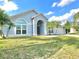 Inviting single-Gathering home featuring a lush green lawn, blue siding and tropical palm trees at 12450 Greco Dr, Orlando, FL 32824