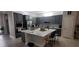 Bright kitchen featuring stainless steel appliances, gray cabinets, a large island, and stylish pendant lighting at 17880 Passionflower Cir, Clermont, FL 34714